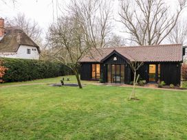 A garden with a house and pathway at Owl Cottage in Woodbridge