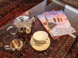 A sitting room with a teapot, cream jug, cup, and magazines at Owl Cottage in Woodbridge