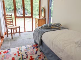 A bedroom with a bed, chair and table at Owl Cottage in Kettleburgh near Framlingham
