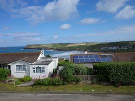 A scenic view of houses with solar panels and ocean at Badgers Cliff in Polzeath