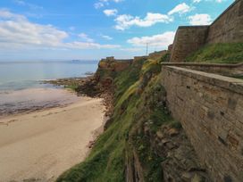 A cliffside beach with water and a stone wall at Chalet 86 North Shields