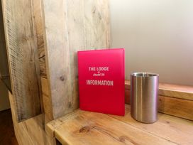 An information folder and a metal cup on a wooden surface at Chalet 86 Tynemouth