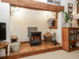 A living room with a fireplace and shelving at Magpie Cottage Worcester