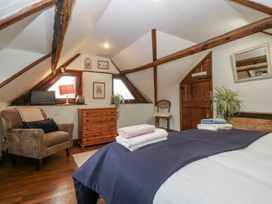A bedroom with a bed and natural wood accents at Magpie Cottage in Worcester