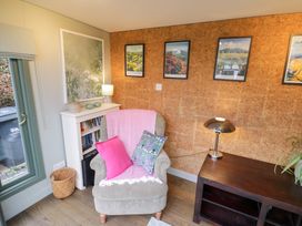 A snug with an armchair and bookshelf at Magpie Cottage Powick near Callow End