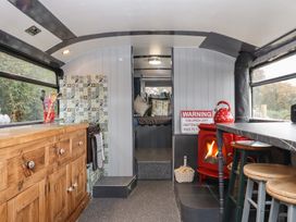 A living room with a wooden cabinet and stove at The Bus on the Hill