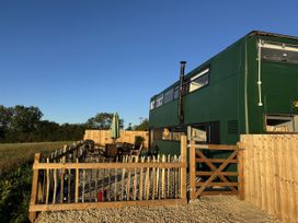An outdoor seating area with a green bus at The Bus on the Hill, Huntsham near Bampton, Devon