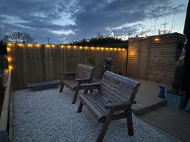 An outdoor area with wooden chairs and gravel surface at The Bus on the Hill in Huntsham near Bampton, Devon