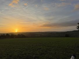 A sunset over fields with trees at The Bus on the Hill in Huntsham near Bampton, Devon