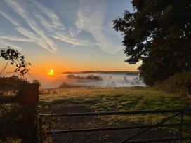 A sunrise over a foggy field with a gate at The Bus on the Hill in Huntsham near Bampton, Devon