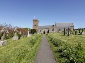 A church and graveyard with a pathway in Crantock at Blake Lodge