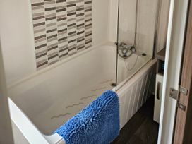 A bathroom with a bathtub and shower setup at 237 Haryn Sands Holiday Park, Padstow