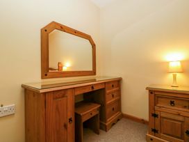 A bedroom with a dressing table and lamp at Orchard Cottage in Corse near Gloucester