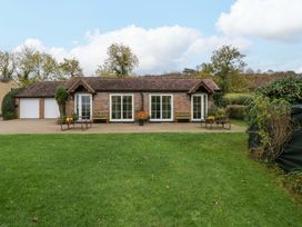 A cottage with benches and potted plants at Orchard Cottage in Corse near Gloucester