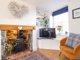 A living room with a fireplace and a television at Periwinkle Cottage in Conwy