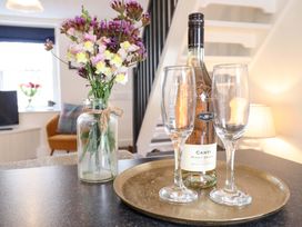 A living room with a tray, wine glasses, and flowers at Periwinkle Cottage, Conwy