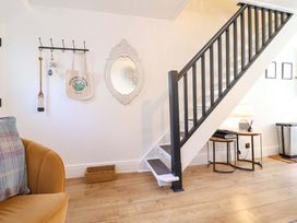 A hallway with a staircase and a coat rack at Periwinkle Cottage Conwy