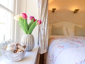 A bedroom with a bed and flowers on a table at Periwinkle Cottage in Conwy