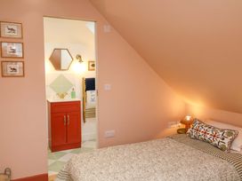 A bedroom with a bed, lamp, and bathroom entrance at 52 Lee Road Aldeburgh