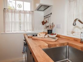 A kitchen with a sink and counter featuring bread and cherries at Copper Mine Cottage in Bodmin