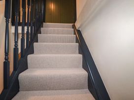 A staircase with carpet and a door at Copper Mine Cottage in Bodmin