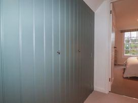 A bedroom with a blue wall and a door leading to another room at Copper Mine Cottage in Bodmin
