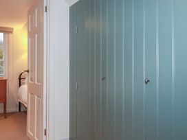 A bedroom with a door, dresser, window and wardrobe at Copper Mine Cottage in Bodmin