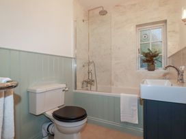 A bathroom with a shower above a bath and a sink at Copper Mine Cottage in Bodmin
