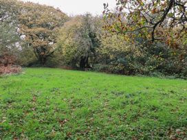 An outdoor area with trees and a bench at Copper Mine Cottage, Bodmin