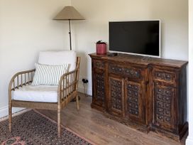A living room with an armchair and television at Copper Mine Cottage in Trelill near Port Isaac