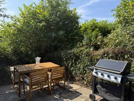 A garden with a table and chairs next to a grill at Copper Mine Cottage in Trelill near Port Isaac