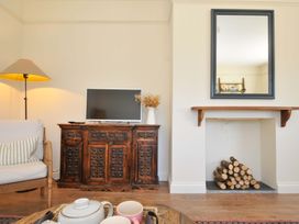 A living room with a television and wooden cabinet at Copper Mine Cottage, Trelill near Port Isaac