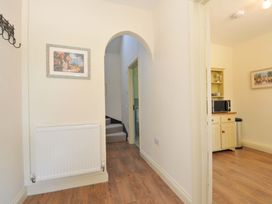 A hallway with a painting and a microwave in the cupboard at Copper Mine Cottage Trelill near Port Isaac