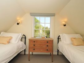 A bedroom with two beds and a window at Copper Mine Cottage, Trelill near Port Isaac