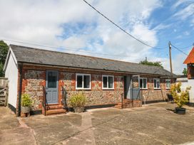 An outdoor view of a stone building with a blue door and windows at The Milk Shed in Plymtree