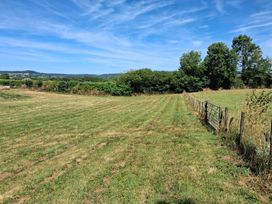 A field with a fence and trees in the background at The Milk Shed in Plymtree