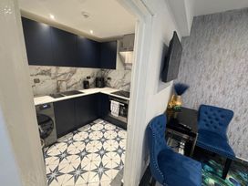 A kitchen with cabinets, sink, stove, washing machine, and chairs at The Old Barn in Manchester