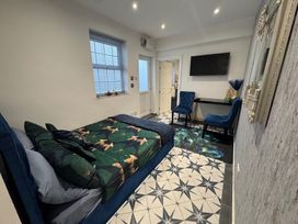 A bedroom with a bed, TV, desk, and chairs at 