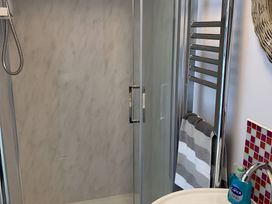 A bathroom with a shower, towel rack, and sink at The Nook