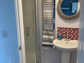 A bathroom with a sink, shower, towel rack, and mirror at The Nook 