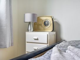 A bedroom with a lamp and radio on a bedside table at The Nook in Praa Sands