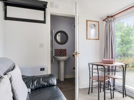 A living room with a dining table and a sink in the background at The Nook in Praa Sands