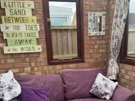 A conservatory with a sofa and wall decor at Quackers in Heacham