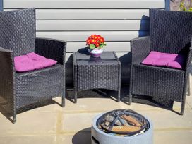 Outdoor seating area with two chairs, a table, and a fire pit at Quackers in Heacham