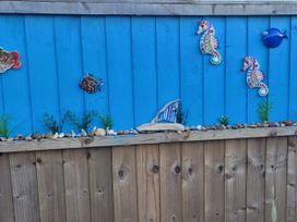 A decorative wooden fence with fish and seahorse art at Quackers in Heacham