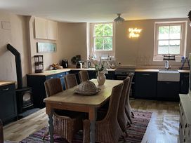 A kitchen featuring a dining table with chairs and a stove at High Dyke Cottage