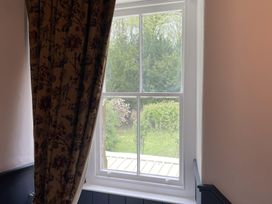 A window with a curtain showing greenery outside at High Dyke Cottage