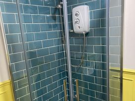 A shower with glass doors and blue tiled walls at High Dyke Cottage