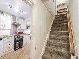 A kitchen with appliances and a staircase at Orchard Cottage in Dawlish
