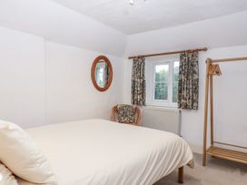 A bedroom with a bed, chair, mirror, and window at Orchard Cottage Dawlish